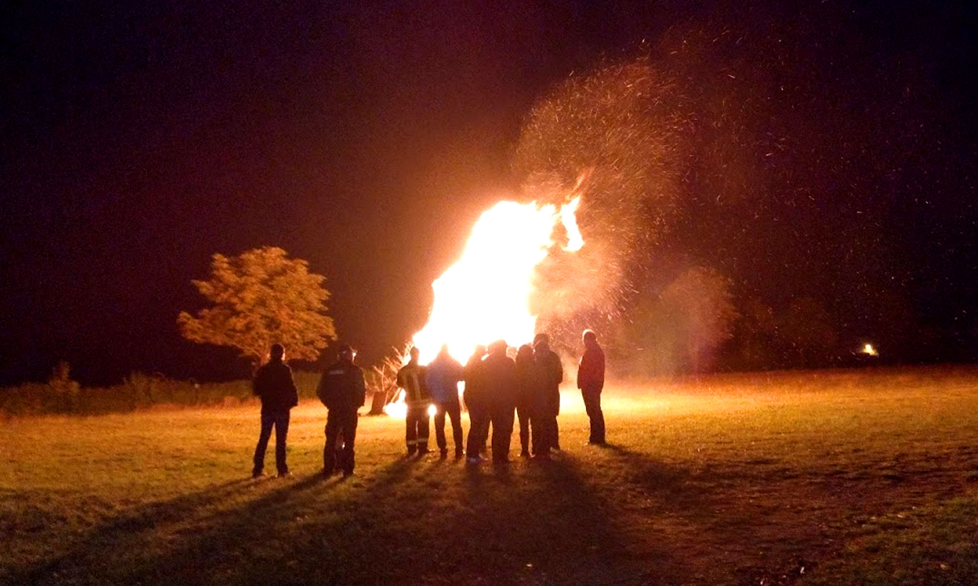 Lagerfeuer mit Leuten die um das Feuser stehen